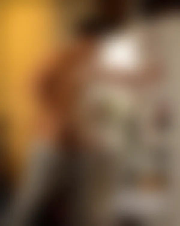 Shirtless muscular man standing confidently beside an open refrigerator with warm yellow light, sweatpants pulled down t
