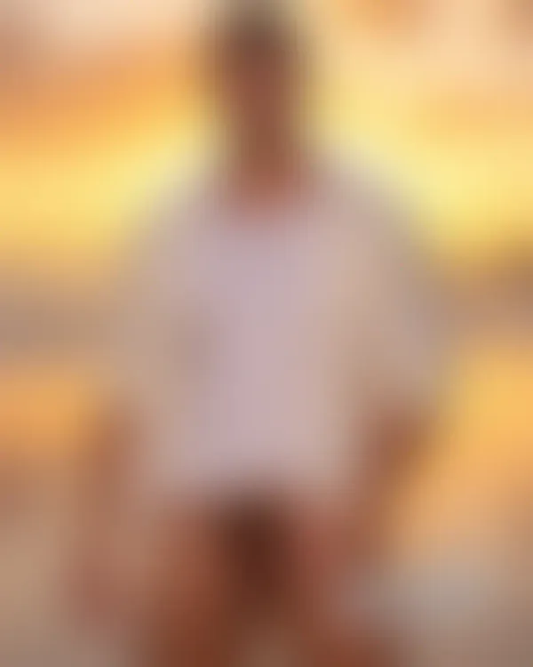 Confident shirtless man on a golden sunset beach with low jeans and one hand near his groin beside two rugged tattooed m