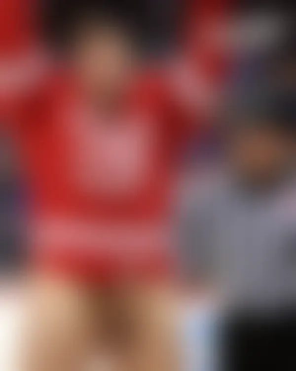 Shirtless muscular men in red Canada jerseys celebrating triumphantly on an icy rink with a referee watching in the back
