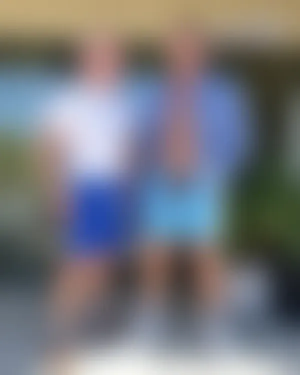 Muscular man on sunny patio, unbuttoned shirt, erect penis visible, blurred greenery background